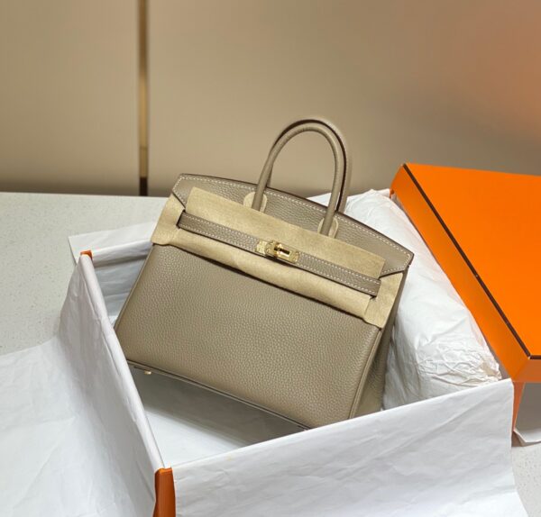 Birkin. Authentic quality luxury bag crafted in genuine leather comes with authenticity card, dust bag and gift bag. Exquisite Craftsmanship and Timeless Elegance: Discover the Allure of the Birkin Bag Large Leather Top Handle. Designed with the actress Jane Birkin in mind, the Birkin bag is a contemporary development of the Kelly bag. Created based on Jane’s suggestions, it was architected to be more significant to fit modern women’s fast-paced life, with several minor yet outstanding adaptations, such as the elongated top handles. The French Birkin 30 bag is a classic touch of elegance to your look! The accessory features a trapeze body, a pebbled leather texture, a hanging key fob, gold-tone hardware, round top handles, a padlock fastening detail, a foldover top with twist-lock closure, a front center logo stamp, an internal zipped pocket, and purse feet.