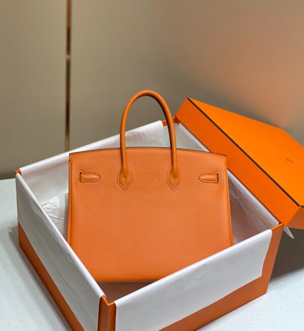Birkin. Authentic quality luxury bag crafted in genuine leather comes with authenticity card, dust bag and gift bag. Exquisite Craftsmanship and Timeless Elegance: Discover the Allure of the Birkin Bag Large Leather Top Handle. Designed with the actress Jane Birkin in mind, the Birkin bag is a contemporary development of the Kelly bag. Created based on Jane’s suggestions, it was architected to be more significant to fit modern women’s fast-paced life, with several minor yet outstanding adaptations, such as the elongated top handles. The French Birkin 30 bag is a classic touch of elegance to your look! The accessory features a trapeze body, a pebbled leather texture, a hanging key fob, gold-tone hardware, round top handles, a padlock fastening detail, a foldover top with twist-lock closure, a front center logo stamp, an internal zipped pocket, and purse feet.
