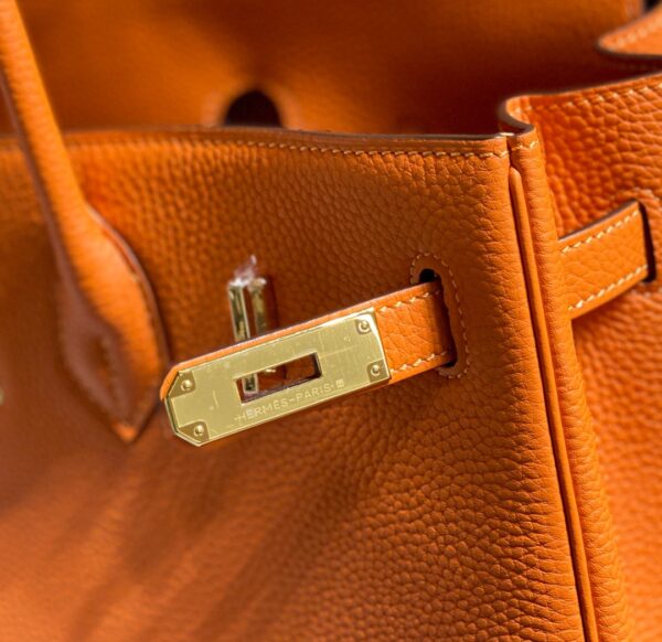 Birkin. Authentic quality luxury bag crafted in genuine leather comes with authenticity card, dust bag and gift bag. Exquisite Craftsmanship and Timeless Elegance: Discover the Allure of the Birkin Bag Large Leather Top Handle. Designed with the actress Jane Birkin in mind, the Birkin bag is a contemporary development of the Kelly bag. Created based on Jane’s suggestions, it was architected to be more significant to fit modern women’s fast-paced life, with several minor yet outstanding adaptations, such as the elongated top handles. The French Birkin 30 bag is a classic touch of elegance to your look! The accessory features a trapeze body, a pebbled leather texture, a hanging key fob, gold-tone hardware, round top handles, a padlock fastening detail, a foldover top with twist-lock closure, a front center logo stamp, an internal zipped pocket, and purse feet.