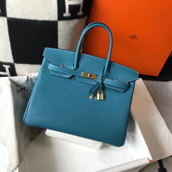 Birkin. Authentic quality luxury bag crafted in genuine leather comes with authenticity card, dust bag and gift bag. Exquisite Craftsmanship and Timeless Elegance: Discover the Allure of the Birkin Bag Large Leather Top Handle. Designed with the actress Jane Birkin in mind, the Birkin bag is a contemporary development of the Kelly bag. Created based on Jane’s suggestions, it was architected to be more significant to fit modern women’s fast-paced life, with several minor yet outstanding adaptations, such as the elongated top handles. The French Birkin 30 bag is a classic touch of elegance to your look! The accessory features a trapeze body, a pebbled leather texture, a hanging key fob, gold-tone hardware, round top handles, a padlock fastening detail, a foldover top with twist-lock closure, a front center logo stamp, an internal zipped pocket, and purse feet.