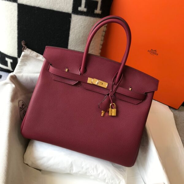 Birkin. Authentic quality luxury bag crafted in genuine leather comes with authenticity card, dust bag and gift bag. Exquisite Craftsmanship and Timeless Elegance: Discover the Allure of the Birkin Bag Large Leather Top Handle. Designed with the actress Jane Birkin in mind, the Birkin bag is a contemporary development of the Kelly bag. Created based on Jane’s suggestions, it was architected to be more significant to fit modern women’s fast-paced life, with several minor yet outstanding adaptations, such as the elongated top handles. The French Birkin 30 bag is a classic touch of elegance to your look! The accessory features a trapeze body, a pebbled leather texture, a hanging key fob, gold-tone hardware, round top handles, a padlock fastening detail, a foldover top with twist-lock closure, a front center logo stamp, an internal zipped pocket, and purse feet.