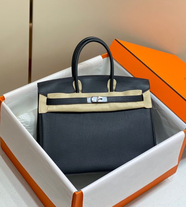 Birkin. Authentic quality luxury bag crafted in genuine leather comes with authenticity card, dust bag and gift bag. Exquisite Craftsmanship and Timeless Elegance: Discover the Allure of the Birkin Bag Large Leather Top Handle. Designed with the actress Jane Birkin in mind, the Birkin bag is a contemporary development of the Kelly bag. Created based on Jane’s suggestions, it was architected to be more significant to fit modern women’s fast-paced life, with several minor yet outstanding adaptations, such as the elongated top handles. The French Birkin 30 bag is a classic touch of elegance to your look! The accessory features a trapeze body, a pebbled leather texture, a hanging key fob, gold-tone hardware, round top handles, a padlock fastening detail, a foldover top with twist-lock closure, a front center logo stamp, an internal zipped pocket, and purse feet.