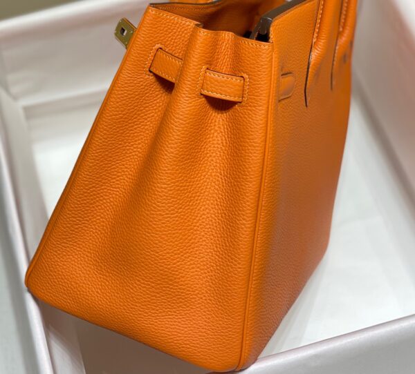 Birkin. Authentic quality luxury bag crafted in genuine leather comes with authenticity card, dust bag and gift bag. Exquisite Craftsmanship and Timeless Elegance: Discover the Allure of the Birkin Bag Large Leather Top Handle. Designed with the actress Jane Birkin in mind, the Birkin bag is a contemporary development of the Kelly bag. Created based on Jane’s suggestions, it was architected to be more significant to fit modern women’s fast-paced life, with several minor yet outstanding adaptations, such as the elongated top handles. The French Birkin 30 bag is a classic touch of elegance to your look! The accessory features a trapeze body, a pebbled leather texture, a hanging key fob, gold-tone hardware, round top handles, a padlock fastening detail, a foldover top with twist-lock closure, a front center logo stamp, an internal zipped pocket, and purse feet.