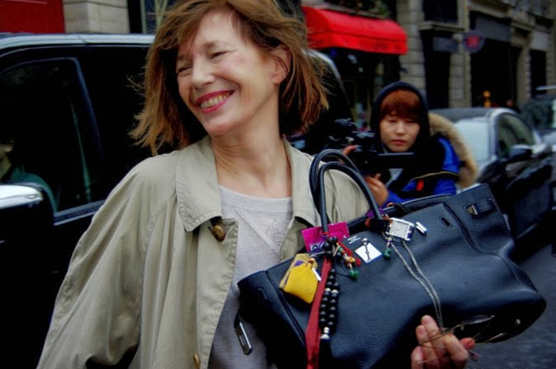 Person holding a black BIRKIN-style handbag in a casual, modern setting Person holding a black BIRKIN-style handbag in a casual, modern setting